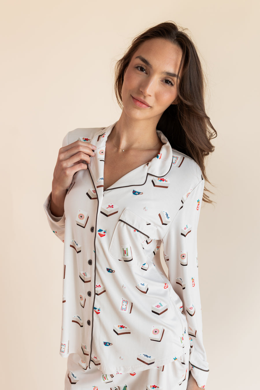 Close up of Model wearing Long-Sleeved Women's Pajama Set in Vanilla Mahjong print with brown trim on a beige background