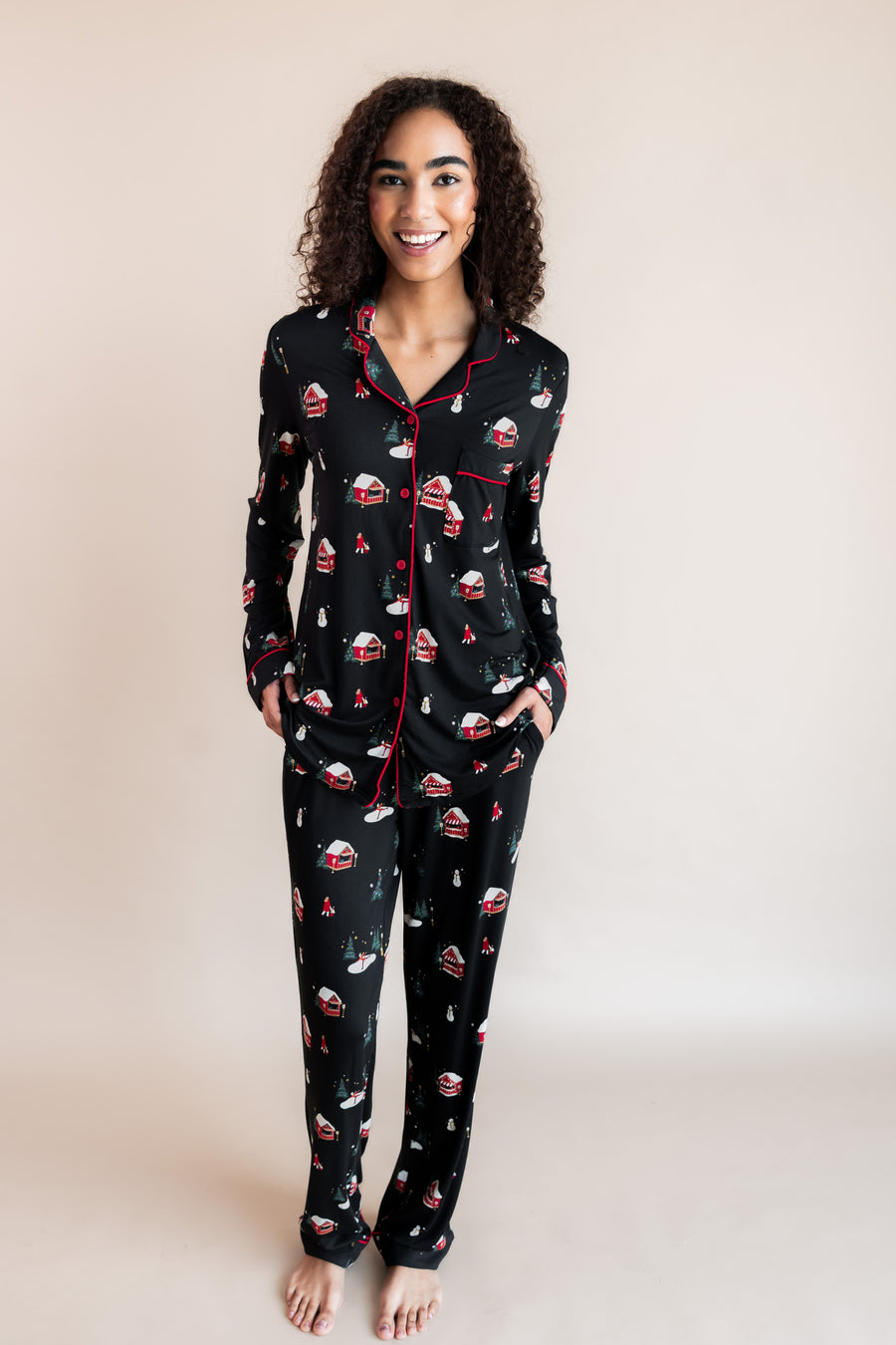 Woman smiling with both of her hands in her pajama pant pockets in winter wonderland print