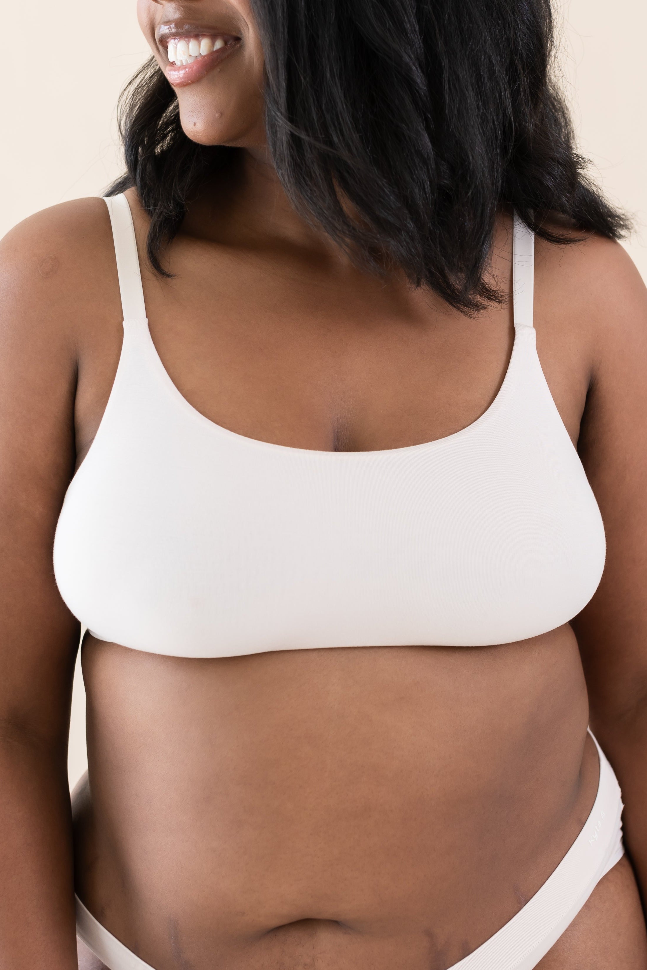 Woman wearing scoop neck bralette and matching underwear in a cream color