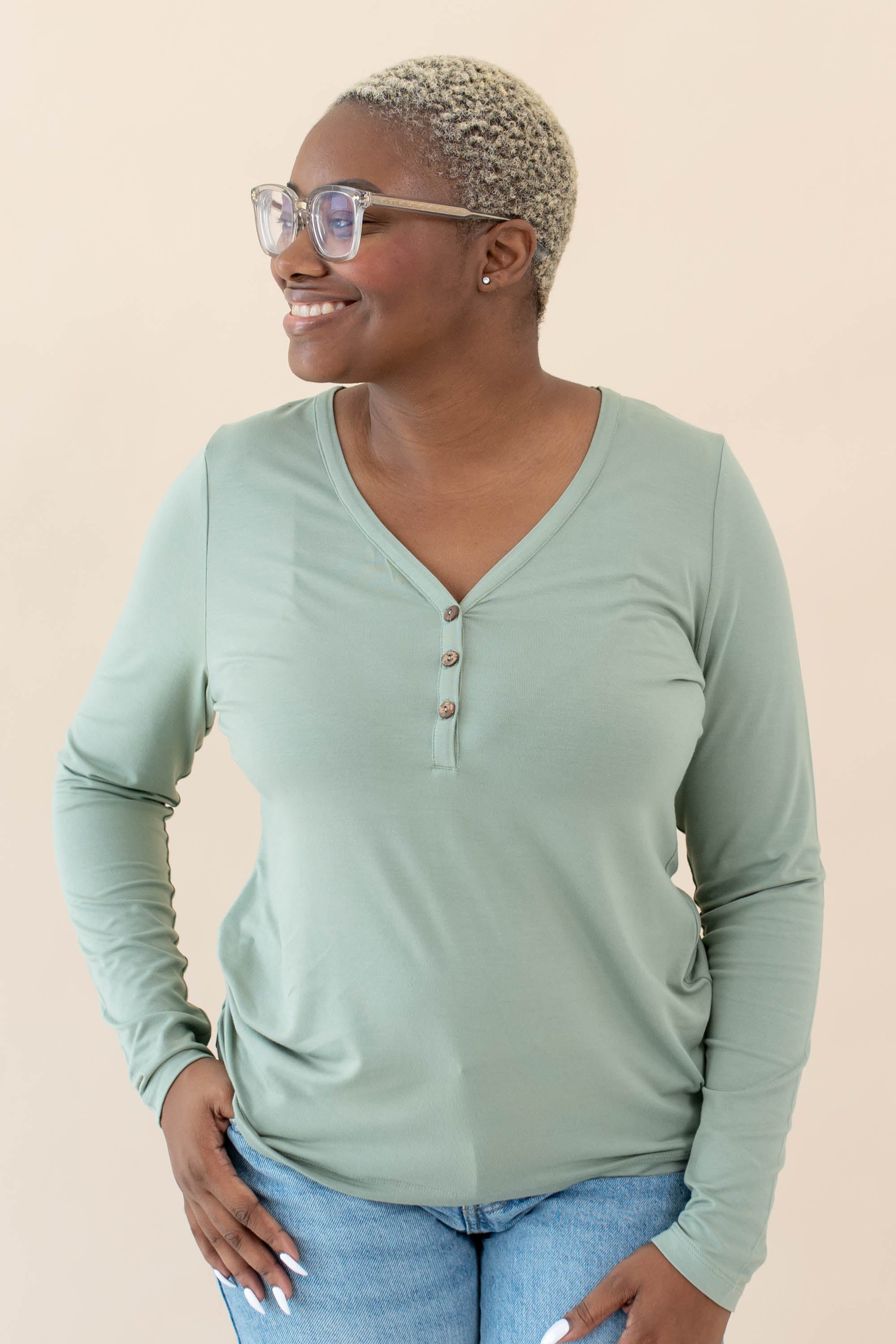 Female model wearing the Women's Long Sleeve Henley Tee in Thyme