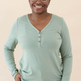 Model wearing the Women's Long Sleeve Henley Tee in Thyme paired with jeans