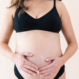Expectant mother with hands on stomach wearing Kyte Baby's Women's Nursing Bra in Midnight