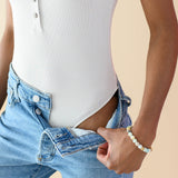 Model displaying the bodysuit thong back of the Women’s Ribbed Henley Bodysuit in Oat