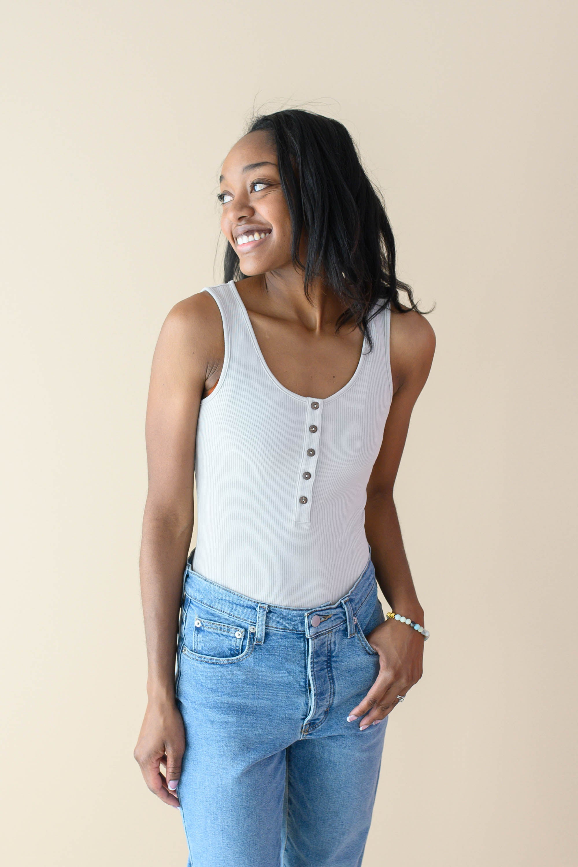 Female wearing the Women’s Ribbed Henley Bodysuit in Oat paired with jeans