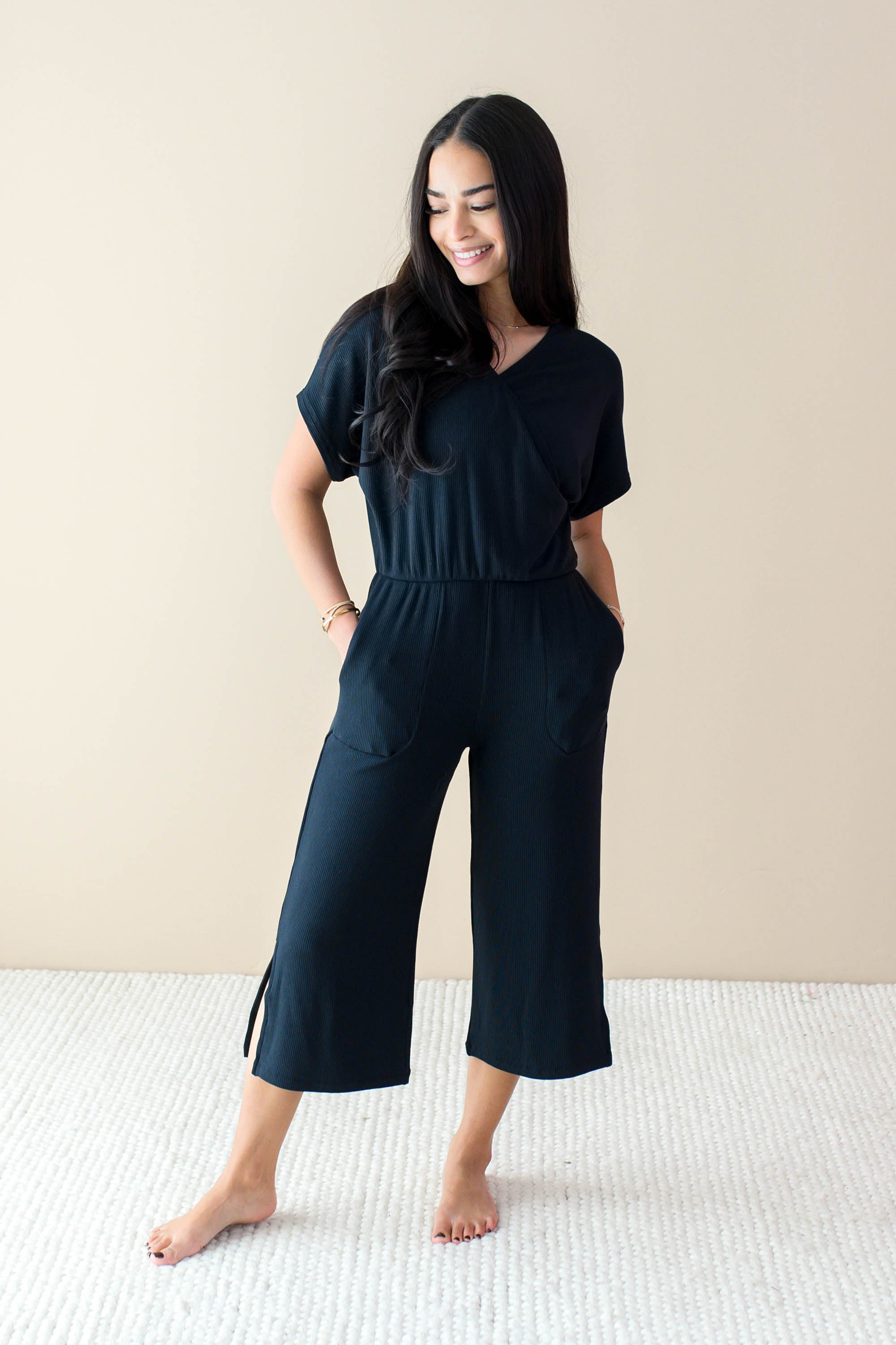 Smiling model wearing the Women's Ribbed Jumpsuit in Midnight with both hands in pockets