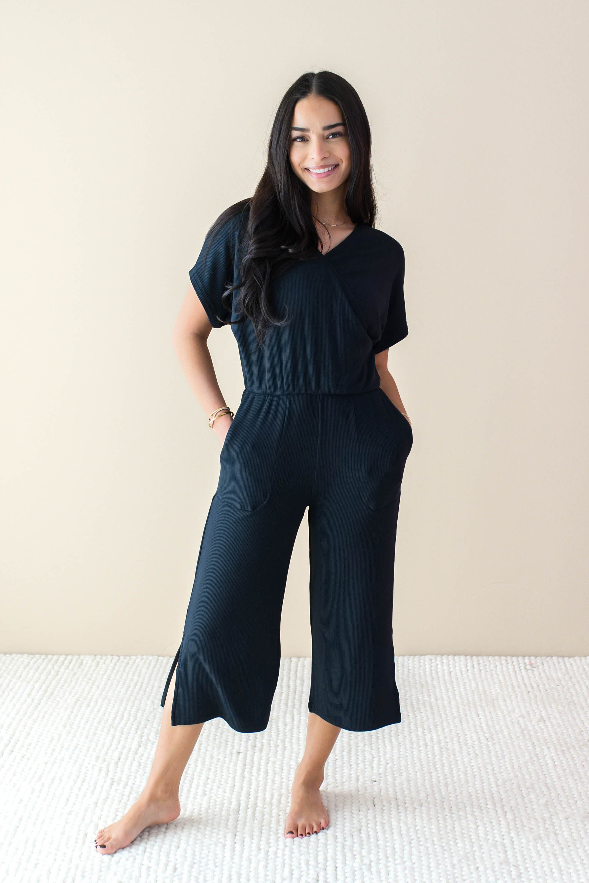 Female model wearing the Women's Ribbed Jumpsuit in Midnight with both hands in pockets