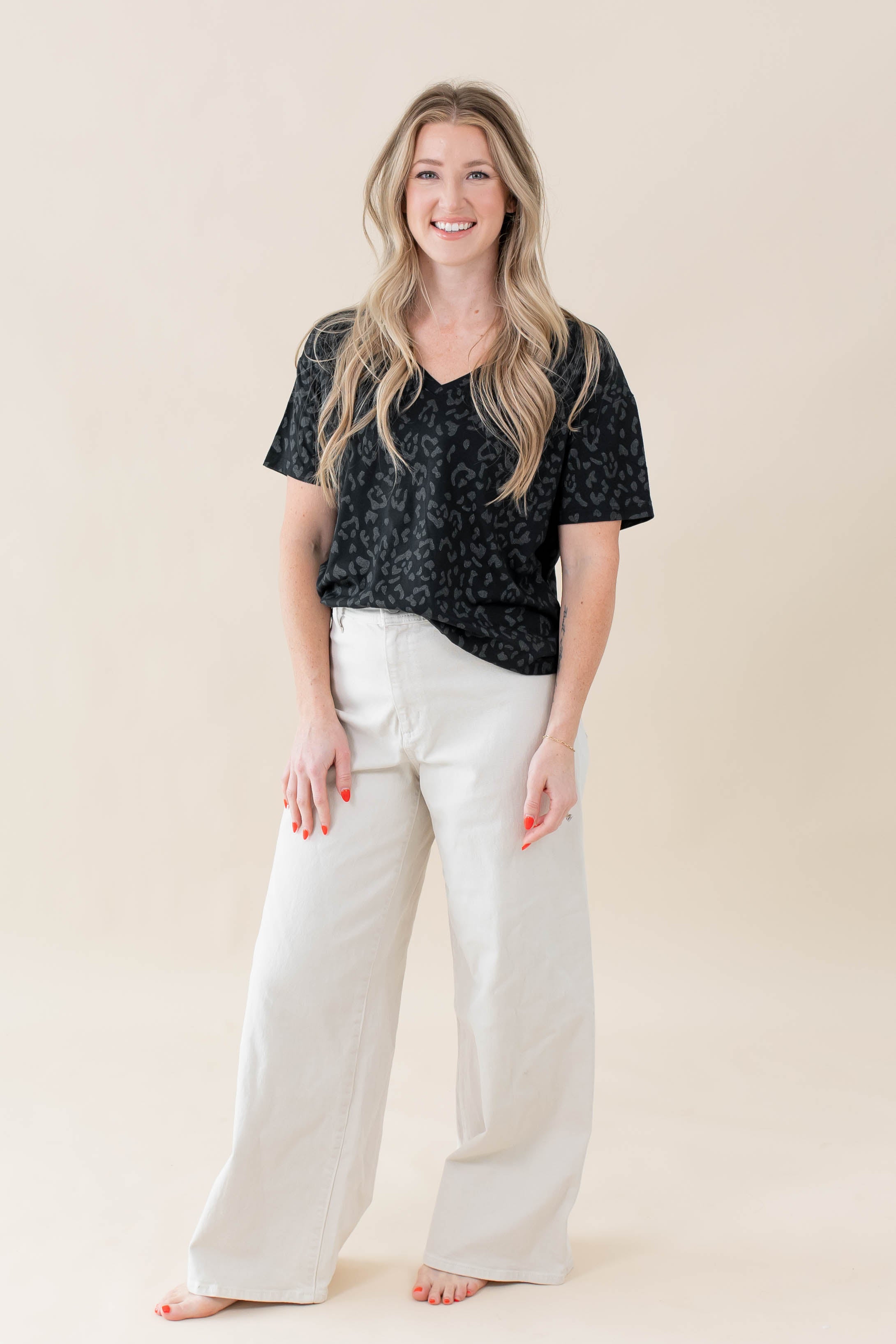Model wearing the Women's Relaxed Fit V-Neck in Midnight Leopard paired with white jeans