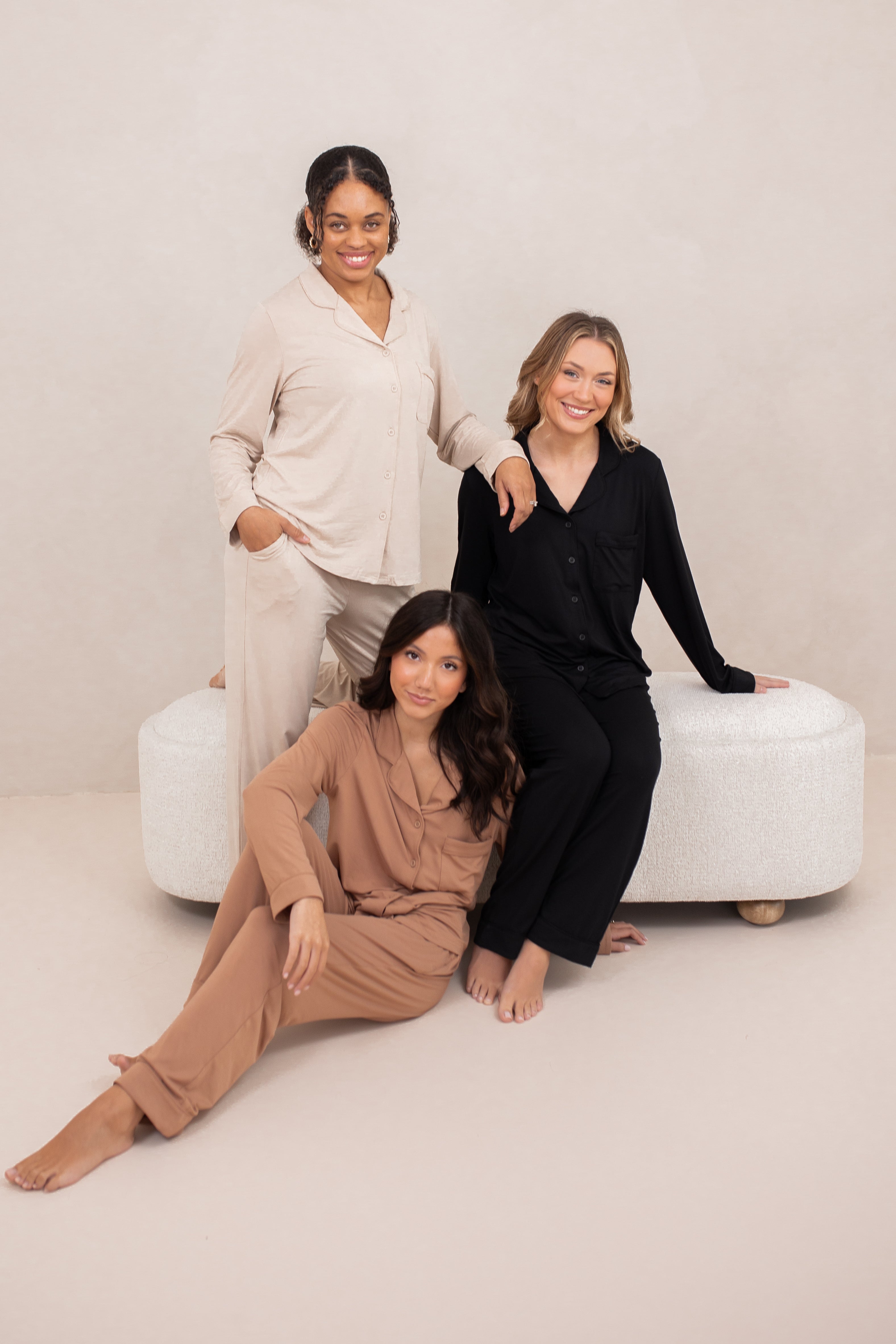 Three female models wearing the Long-Sleeved Women's Pajama Set in Latte with Latte Trim, Midnight with Midnight Trim and Bisque with Bisque Trim