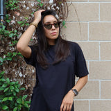 Close up of woman wearing Women’s Biker Short Set in Midnight against a brick wall with greenery