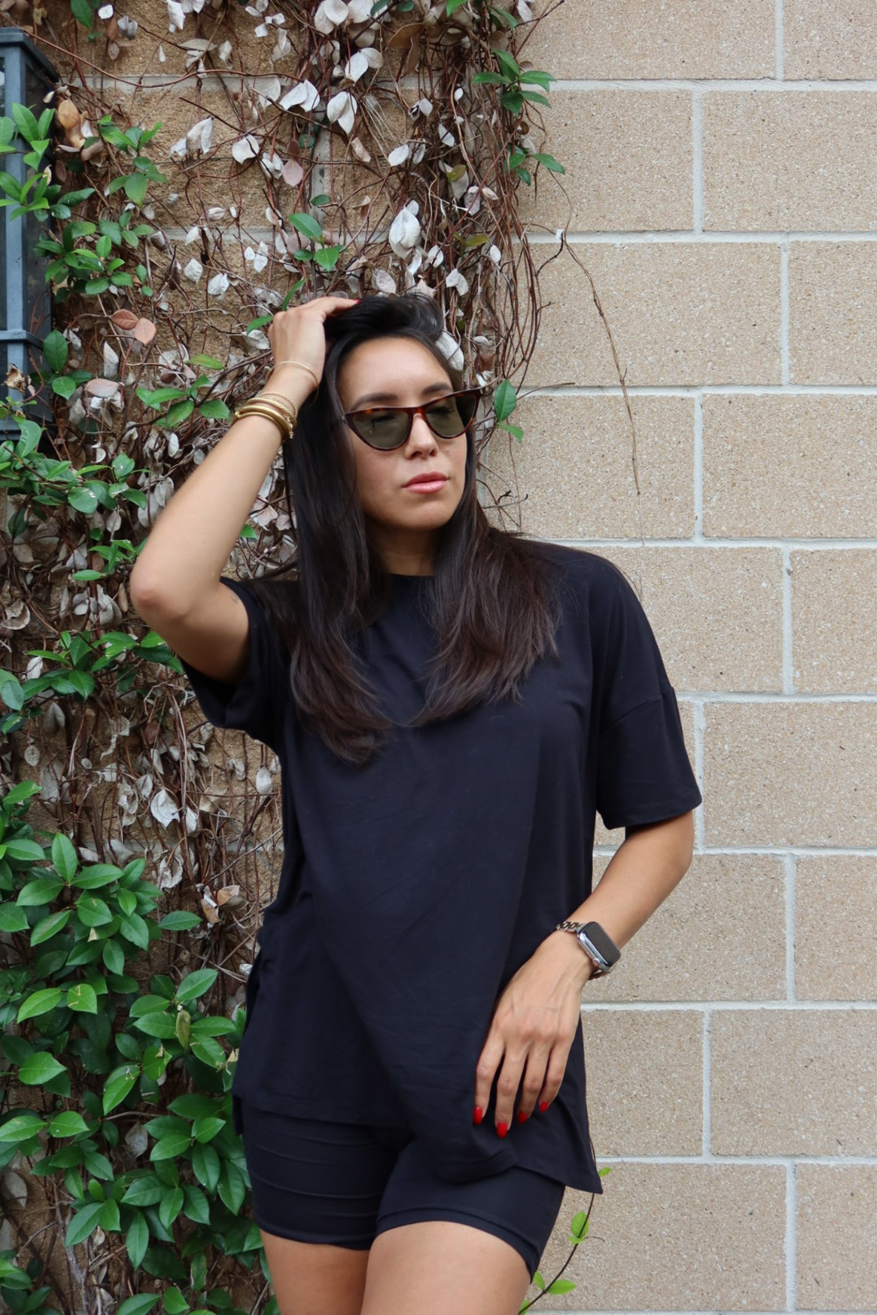 Close up of woman wearing Women’s Biker Short Set in Midnight against a brick wall with greenery