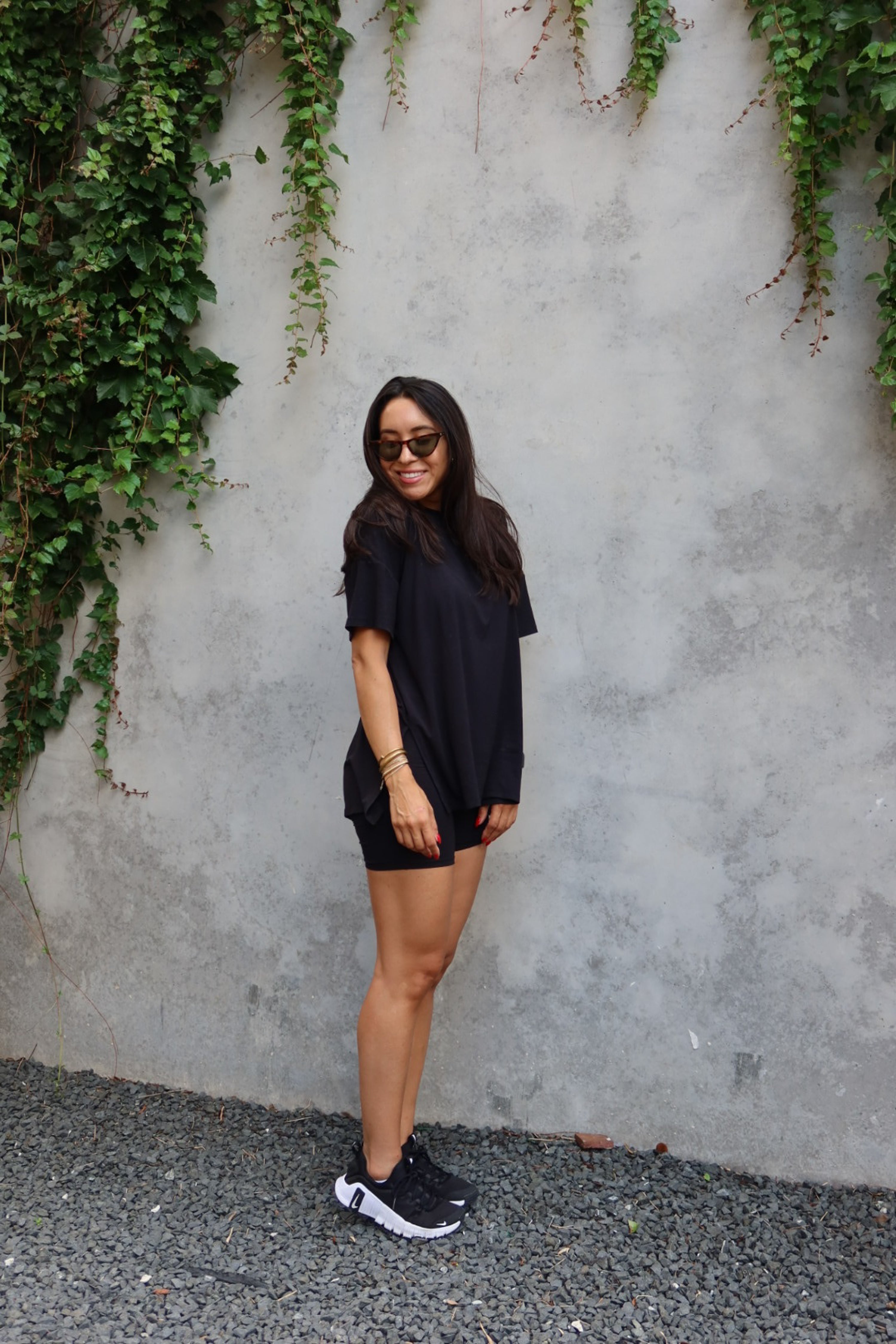 Woman modeling Women’s Biker Short Set in Midnight against a concrete wall with trailing vines