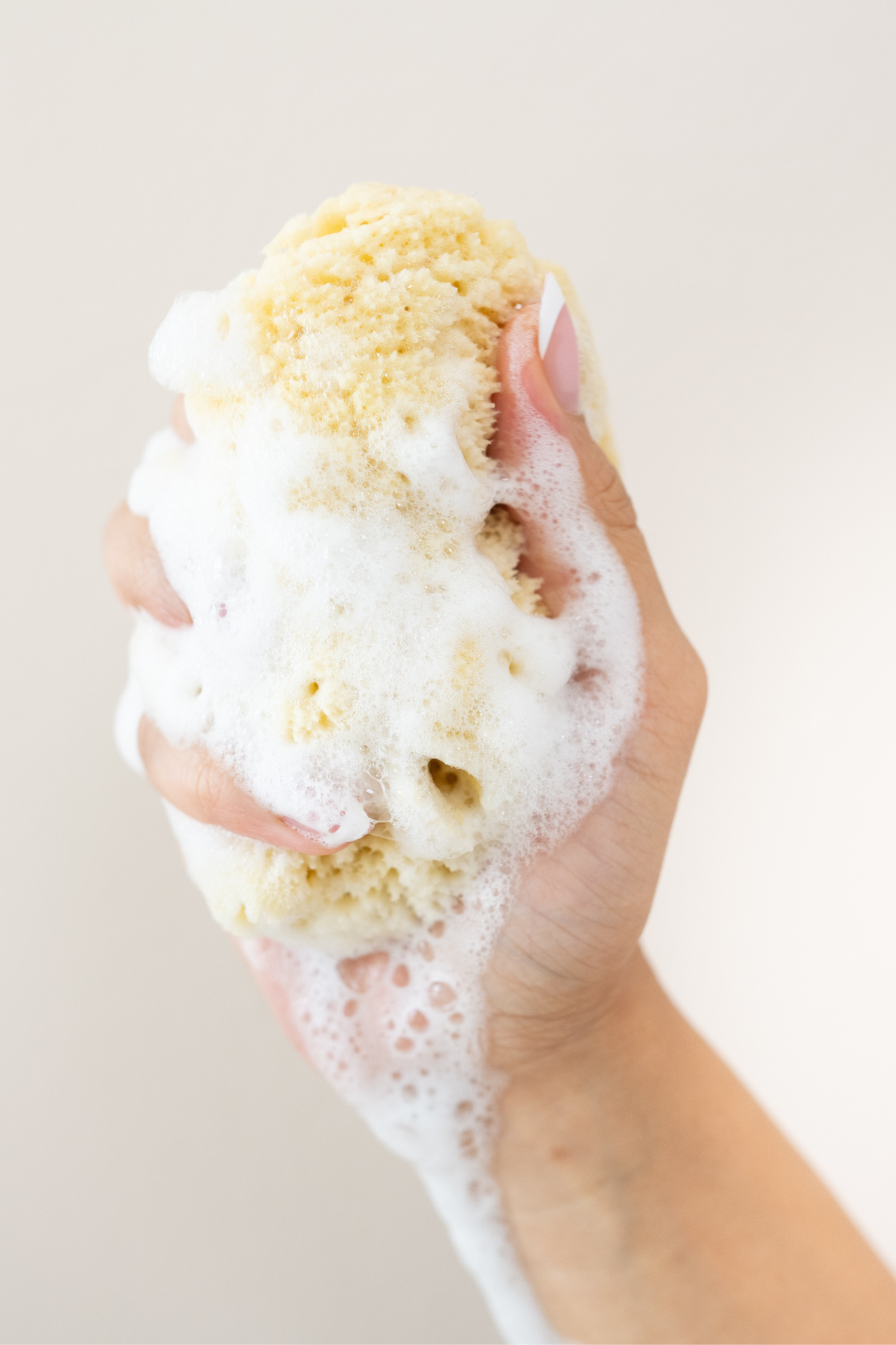 Woman's hand squeezing the Kyte Living Sea Sponge with soap