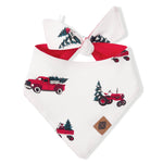 A white pet bandana with a red tie and a holiday-themed print of vintage red trucks and tractors carrying Christmas trees, shown on a plain white background.