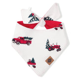 A white pet bandana with a red tie and a holiday-themed print of vintage red trucks and tractors carrying Christmas trees, shown on a plain white background.