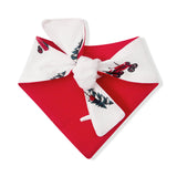 A red and white bandana-style pet bow tie featuring a printed pattern of red motorcycles, green holly leaves, and pine trees, shown on a plain white background.