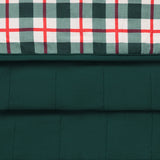 A close-up of a quilted fabric product showing two pattern sections: a dark green plaid top panel with white and red intersecting stripes, and a solid dark green quilted lower section.
