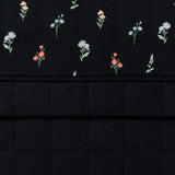 Close-up view of folded Quilt Blanket in Midnight Flower 2.5 displaying the quilted texture on one side and a smooth fabric on the other