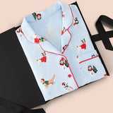 Blue Long-Sleeved Women's Pajama Set in Holiday Pups print packed in a box on a beige background