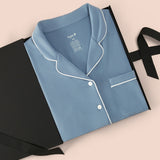 Long-Sleeved Women's Pajama Set in Slate with Cloud Trim packed in a box on a beige background