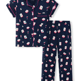 A two-piece women's pajama set featuring a short-sleeve button-front top and matching long pants in navy blue with a repeating pattern of red, white, and pink cocktail glasses and mahjong tiles, finished with pink piping.