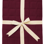 Product photo of the Kyte Bamboo Throw Blanket in Burgundy 2.5 while wrapped in an ivory bow