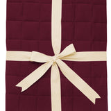 Product photo of the Kyte Bamboo Throw Blanket in Burgundy 2.5 while wrapped in an ivory bow