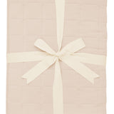 Product photo of the Kyte Bamboo Throw Blanket in Bisque 2.5 while wrapped in an ivory bow