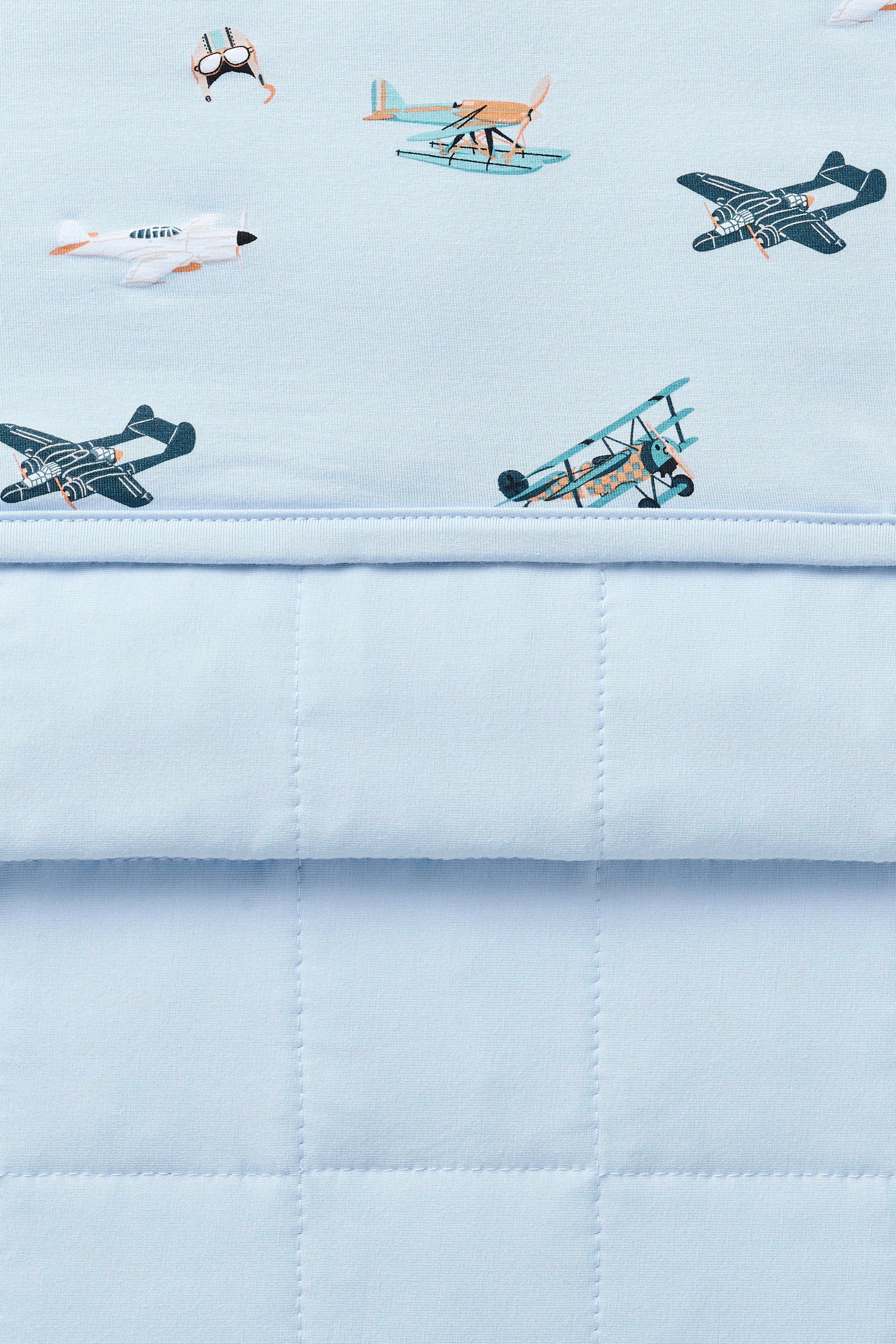 Close up of Bamboo Throw Blanket in Take Off 1.0 showing both quilted backing and printed side