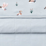 Close up of the Youth Blanket in Mallard Duck 1.0 showing the light blue quilted backing and patterned smooth top layer