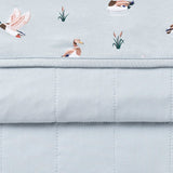 Close up of the Youth Blanket in Mallard Duck 1.0 showing the light blue quilted backing and patterned smooth top layer