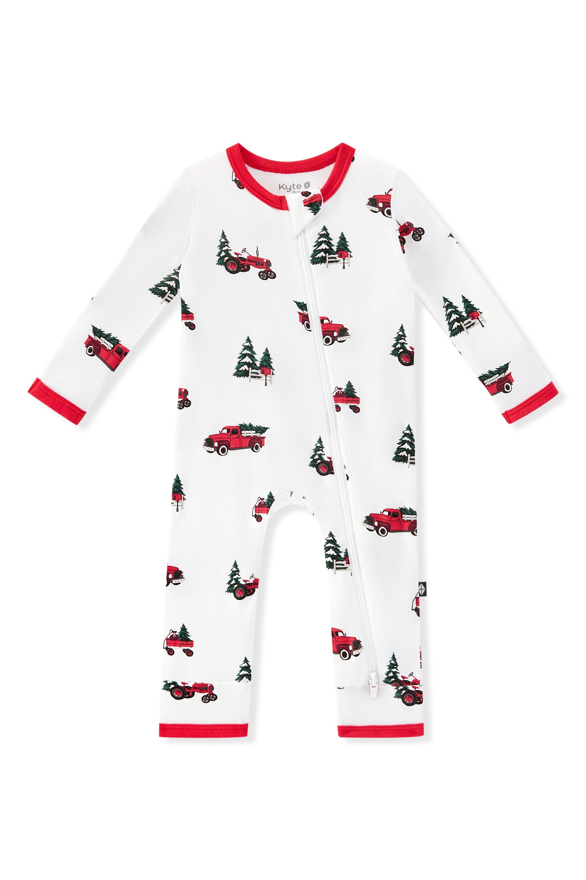 A zippered romper in white, featuring a repeating pattern of red pickup trucks carrying Christmas trees and red trim on the collar, cuffs, and ankles shown on a white background