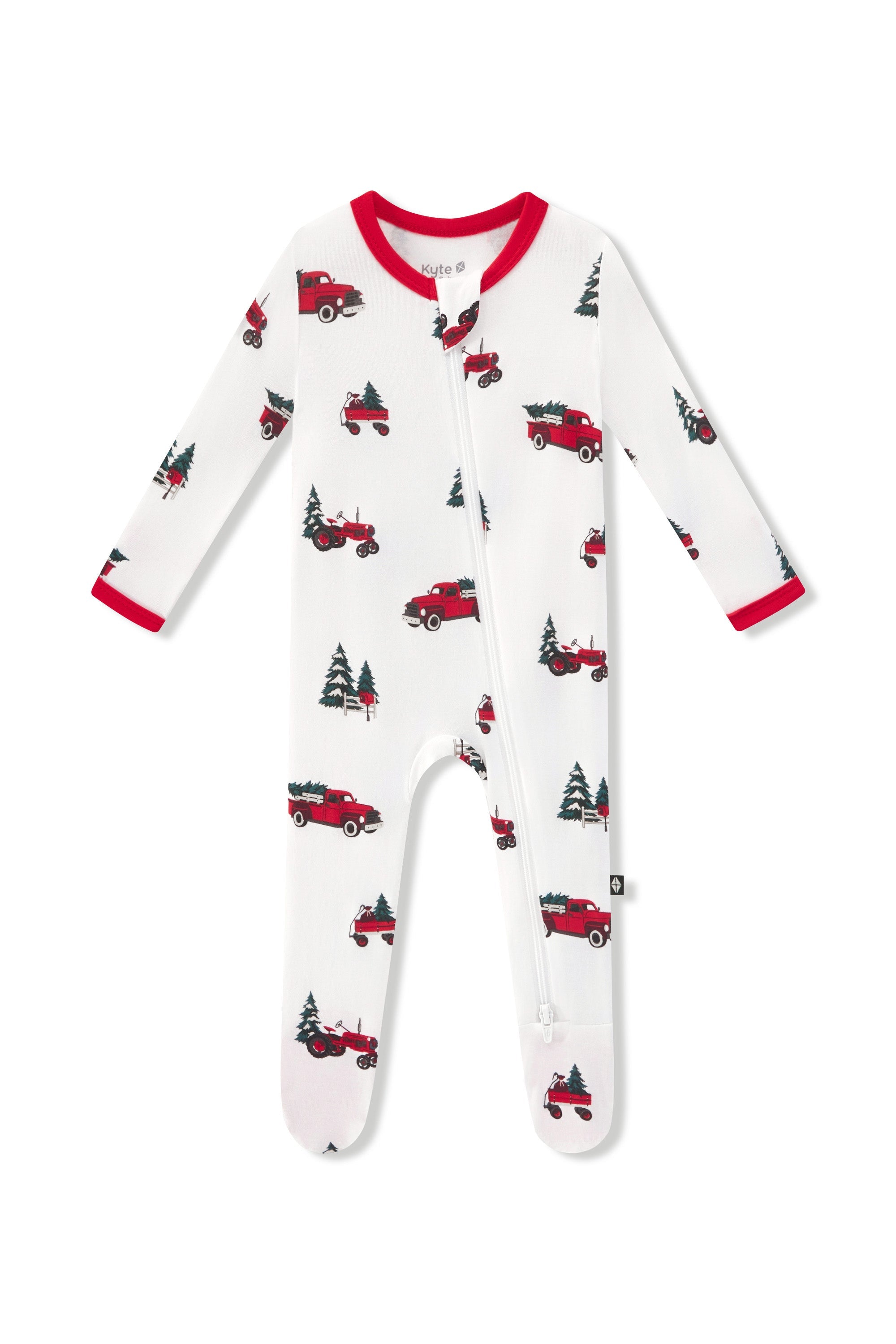 A white zippered footie with a red and green Christmas truck and pine tree pattern, featuring red trim on the collar and cuffs shown on a white background