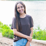 Smiling model standing by a lake wearing the Women's Crew Neck Tee in Espresso