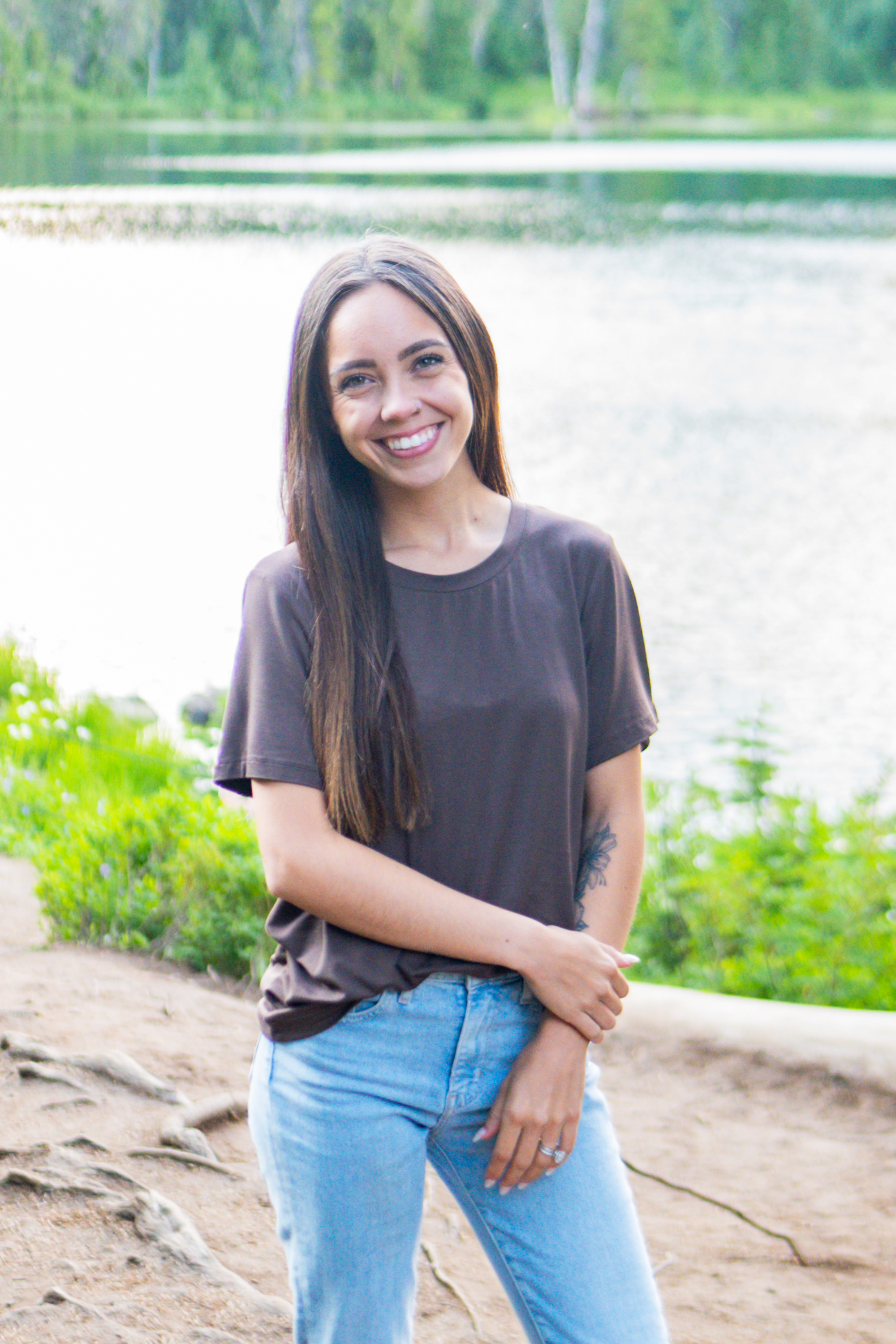 Smiling model standing by a lake wearing the Women's Crew Neck Tee in Espresso