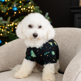 Small white dog sitting on a chair in front of a Christmas tree wearing the Dog Tee in Twinkle Tree