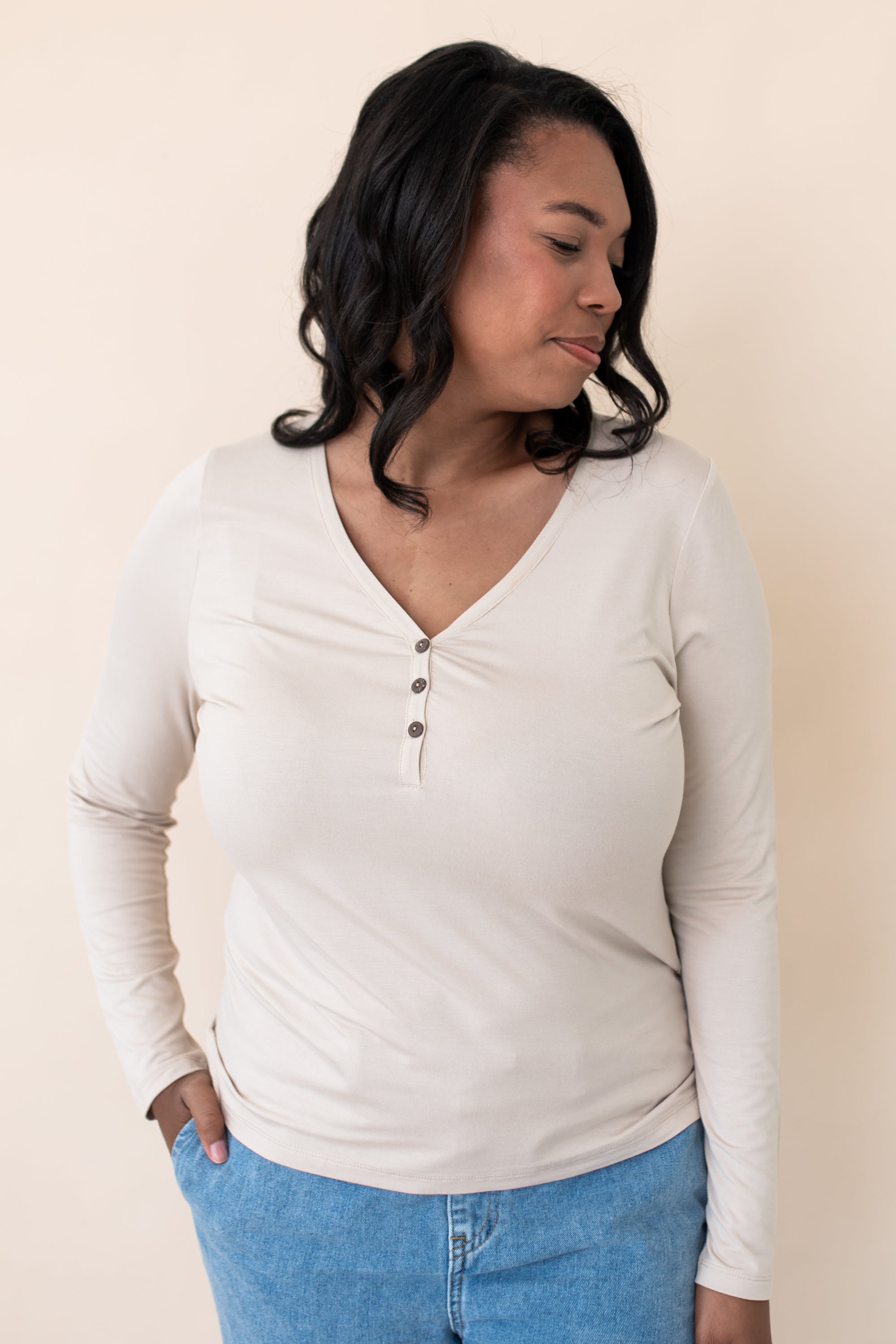 Woman modeling the Kyte Women's Long Sleeve Henley Tee in Bisque paired with light jeans