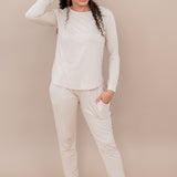 Woman wearing a beige long-sleeve top and pants against a beige background