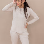 Woman wearing a beige long-sleeve lounge top and pants against a beige background
