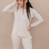 Woman wearing a beige long-sleeve lounge top and pants against a beige background