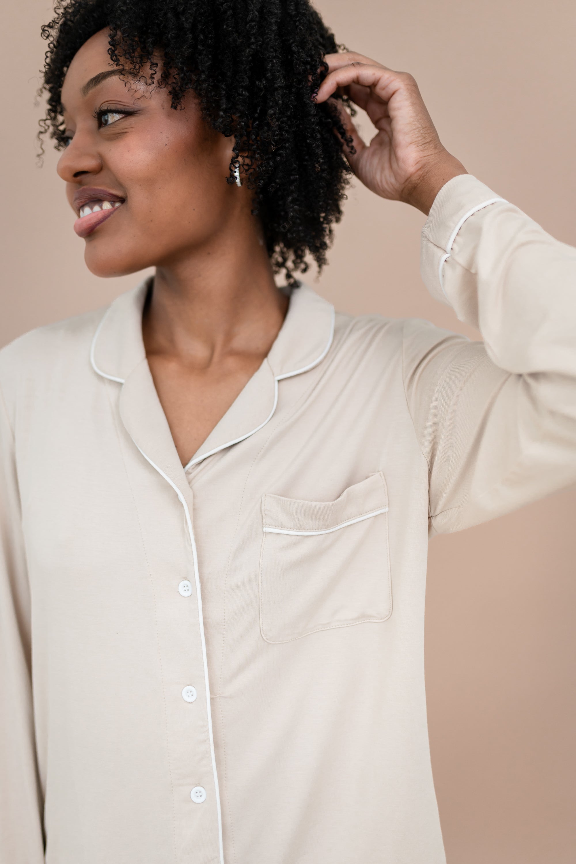 Woman wearing a beige button-up pajama shirt against a beige background