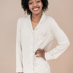 Woman wearing a bisque pajama set with hand on hip against a beige background