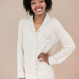 Woman wearing a bisque pajama set with hand on hip against a beige background