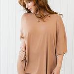 Woman wearing a tan outfit against a white background