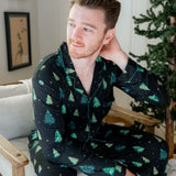 Model sitting on a white chair with hand in hair while wearing the Men's Long Sleeve Pajama Set in Twinkle Tree