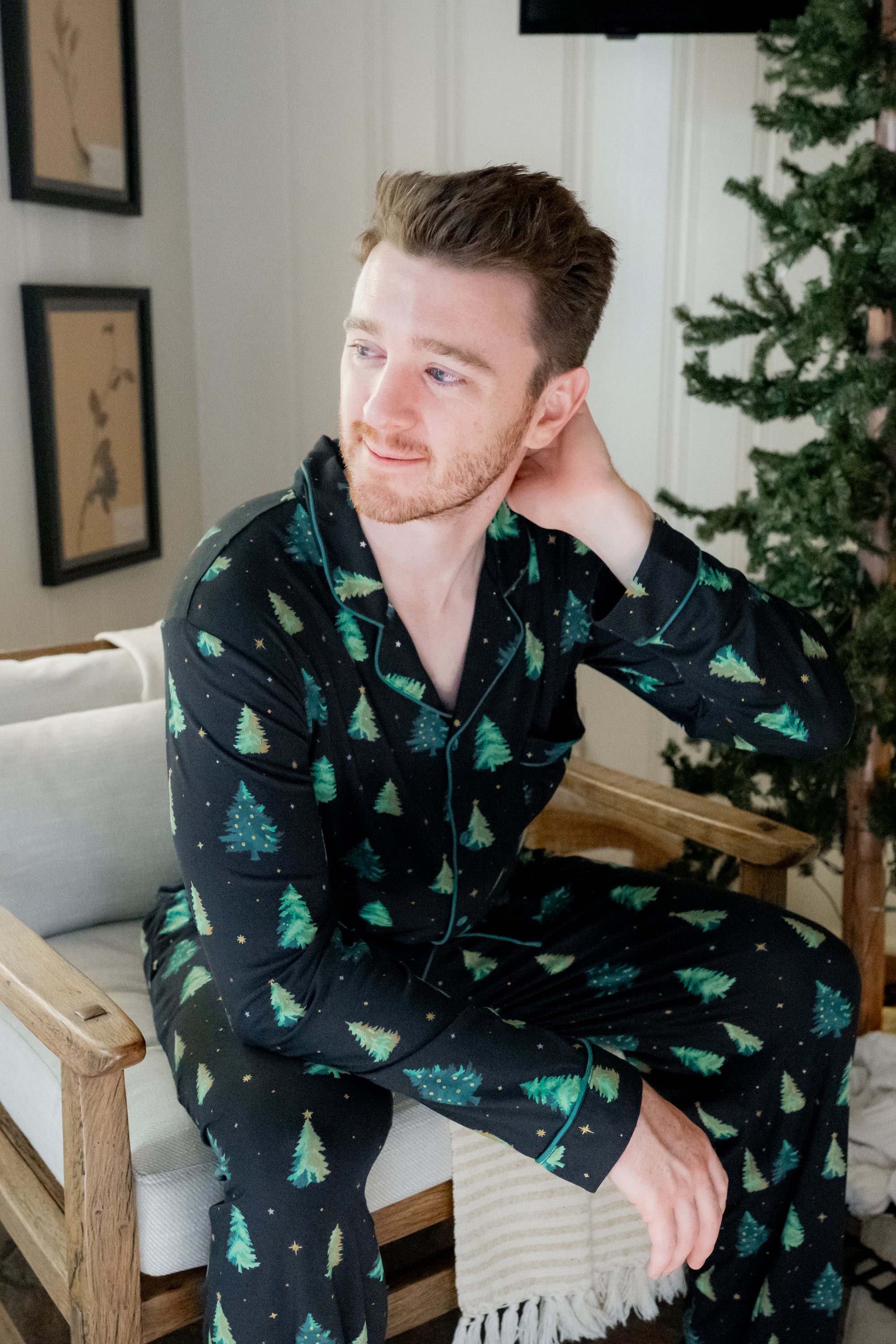 Model sitting on a white chair with hand in hair while wearing the Men's Long Sleeve Pajama Set in Twinkle Tree