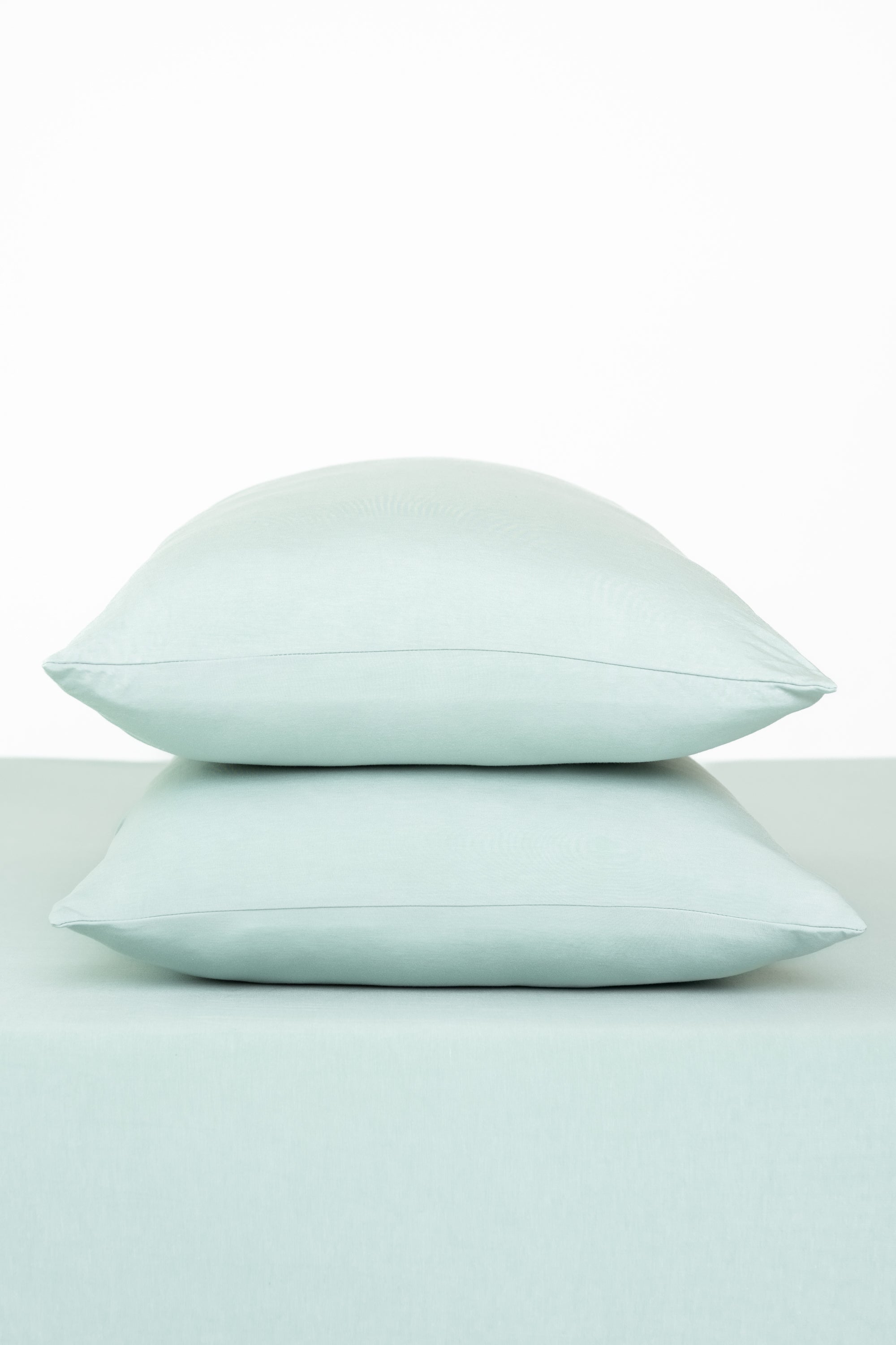 Fitted Sheet with Pillowcases in Sage. Showing 2 pillows stacked on a sheet