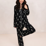 Model standing with one leg up while wearing the Long-Sleeve Women's Pajama Set in Skeleton