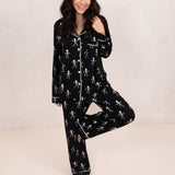 Model standing with one leg up while wearing the Long-Sleeve Women's Pajama Set in Skeleton