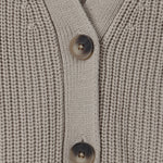 Close-up of a ribbed knit cardigan sweater in a light taupe-beige color, featuring two dark brown buttons on the front.
