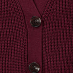 Close-up of a ribbed knit cardigan in deep burgundy with two dark buttons, showing the texture and neckline detail.